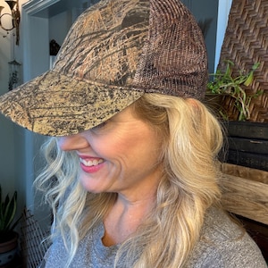Puede incluir: Gorra de b&eacute;isbol con estampado de camuflaje y parte trasera de malla marr&oacute;n. La gorra presenta una visera curva y un patr&oacute;n de tonos marrones, beige y verdes. La parte trasera de malla proporciona ventilaci&oacute;n. Adecuada para actividades al aire libre.