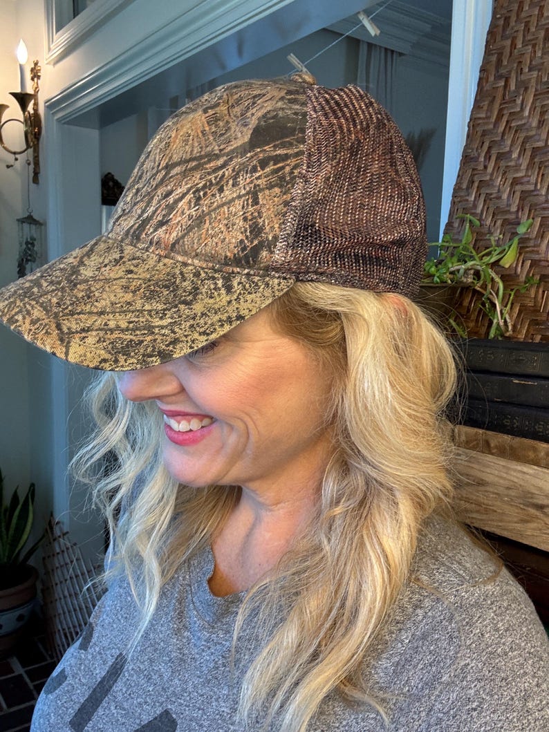 Puede incluir: Gorra de b&eacute;isbol con estampado de camuflaje y parte trasera de malla marr&oacute;n. La gorra presenta una visera curva y un patr&oacute;n de tonos marrones, beige y verdes. La parte trasera de malla proporciona ventilaci&oacute;n. Adecuada para actividades al aire libre.