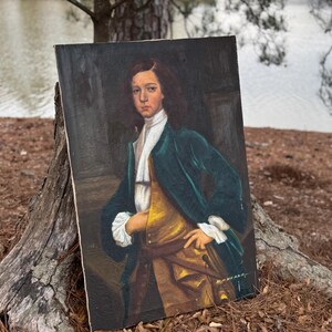Pode incluir: Pintura a &oacute;leo de uma pessoa jovem com casaco verde-azulado, colete dourado e camisa branca. O retrato &eacute; ambientado em um fundo escuro, com as m&atilde;os do sujeito apoiadas na cintura. A pintura &eacute; assinada "H. HEANE" no canto inferior direito.