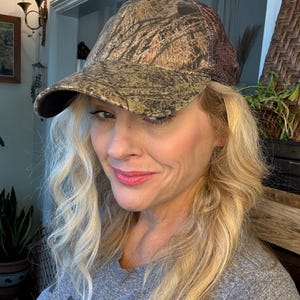 Puede incluir: Gorra de b&eacute;isbol de camuflaje con la parte trasera de malla marr&oacute;n y una visera curva. La gorra presenta un patr&oacute;n de marr&oacute;n, dorado y verde, creando un dise&ntilde;o de camuflaje de bosque. El sombrero es de estilo cl&aacute;sico de seis paneles.