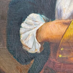 Pode incluir: Close-up de um fragmento de pintura a &oacute;leo vintage. A imagem mostra o bra&ccedil;o e a m&atilde;o de uma pessoa, com uma manga branca com babados. A pessoa est&aacute; vestindo um colete amarelo e um casaco escuro. A pintura tem rachaduras vis&iacute;veis.