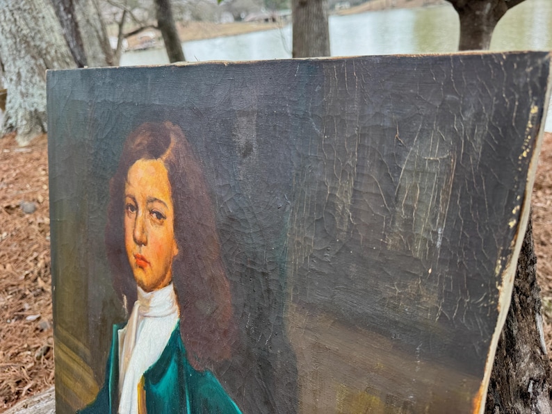 Pode incluir: Uma pintura de retrato antigo de uma pessoa com cabelo castanho comprido, usando uma camisa de colarinho branco e um casaco verde-azulado. A pintura tem um fundo escuro e &eacute; exibida em uma moldura de madeira.