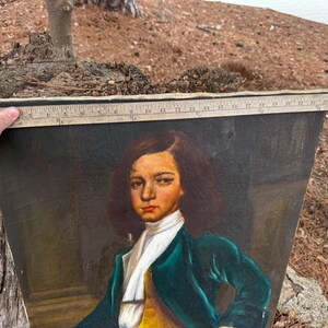 Pode incluir: Um retrato antigo de uma pessoa com um casaco verde, gola branca e colete amarelo. A pintura &eacute; segurada por uma m&atilde;o, e uma r&eacute;gua &eacute; colocada no topo. O sujeito tem cabelo castanho e uma express&atilde;o s&eacute;ria.