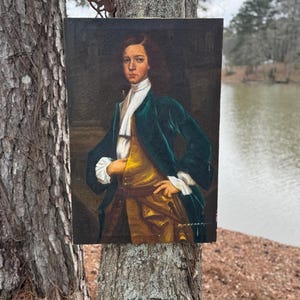Pode incluir: Uma pintura a &oacute;leo de um jovem com um casaco de veludo verde, colete dourado e gravata branca. O retrato est&aacute; sobre um fundo escuro, com a m&atilde;o do sujeito na anca. A pintura est&aacute; montada numa moldura de madeira.