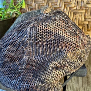 Puede incluir: Gorra de estilo newsboy de malla marr&oacute;n, negra y beige. La gorra tiene una corona redondeada y una visera corta y r&iacute;gida. El dise&ntilde;o de malla proporciona ventilaci&oacute;n. La gorra est&aacute; colocada sobre una superficie de madera.