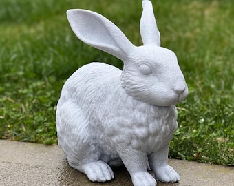 May include: A white ceramic rabbit sculpture with a detailed, textured fur design. The rabbit is sitting with its ears upright and its head tilted slightly to the side.