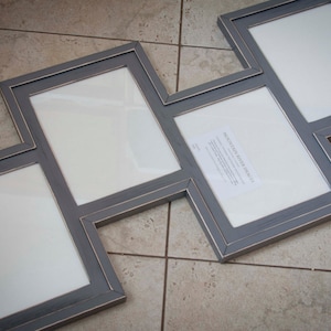May include: A multi-photo frame with a gray finish and a unique zig-zag design. The frame has four openings with white matting. The frame is made of wood and has a distressed look. The frame is designed to hold multiple photos.