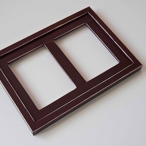 May include: A dark brown wooden picture frame with two openings. The frame is made of dark wood with a smooth finish.