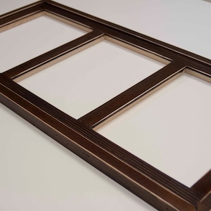 May include: A dark brown wooden picture frame with three openings. The frame has a decorative, grooved edge.