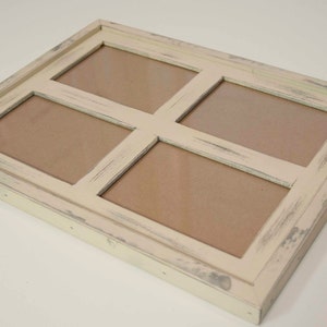 May include: A rectangular, off-white picture frame with four openings. The frame has a distressed, vintage look with visible wear and tear. The openings are filled with a neutral-colored backing, ready for photos or artwork. The frame is designed to hold multiple images.