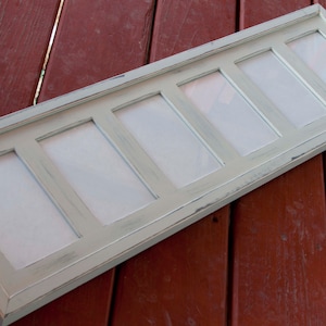 May include: A rectangular, multi-photo picture frame with six openings. The frame is painted a light, distressed green-gray color. The frame is made of wood and is designed to hold multiple photos, creating a collage effect.