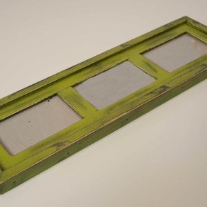 May include: A green wooden picture frame with three openings for photos. The frame has a distressed finish and is perfect for displaying family photos or artwork.