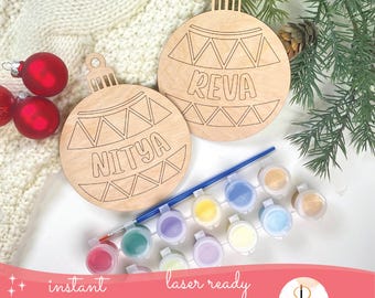 May include: Two unfinished wooden Christmas ornaments with the names "NITYA" and "REVA" laser-cut into them. A paint set with a paintbrush and red glass ornaments are also visible. The words "instant download" and "laser ready SVG files" are also visible.