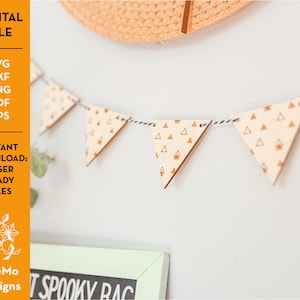 May include: A wooden triangle banner with a pattern of small orange triangles. The banner is strung with black and white twine and is hanging on a white wall. The text "IT SPOOKY RAC" is visible on a black chalkboard in the background.