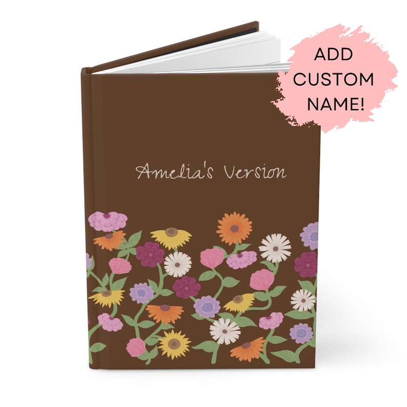 May include: A brown journal with the text "Amelia's Version" and a floral design. The floral design includes pink, orange, yellow, purple, and white flowers. The journal has a hardcover and a spiral binding.