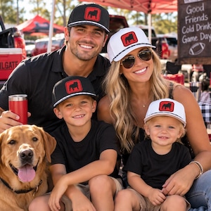May include: A collection of baseball caps featuring a red square patch with a black bulldog silhouette. The caps have a black or white crown, a black and white checkered trim along the brim, and a structured front panel with a mesh back design.