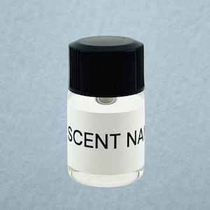 May include: A small, clear glass bottle with a black screw-top lid. The bottle features a white rectangular label wrapped around the center, printed with the black text SCENT NAME in a bold, sans-serif font. The container is empty and transparent.