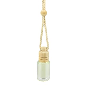 May include: A small, clear glass bottle with a light green liquid inside, topped with a cylindrical wooden cap. The bottle is suspended by a thick, beige twisted rope cord that features a small, round wooden bead accent near the top.