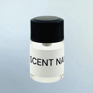 May include: A small, clear glass bottle with a black ribbed screw-top cap. The bottle features a white rectangular label wrapped around the center with the text SCENT NAME printed in bold, black, sans-serif capital letters on the front.