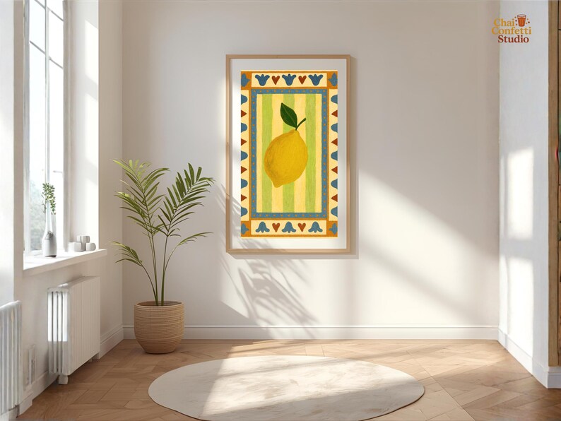 May include: A framed art print featuring a yellow lemon with a green leaf, set against a striped yellow and green background. The artwork is bordered by a decorative blue and orange pattern. The print is displayed in a bright, airy room with a plant and a round rug.