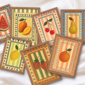 May include: A collection of framed fruit art prints. Each print features a different fruit, including a watermelon, mango, cherries, pear, lemon, strawberries, and an orange. The prints have a striped background and are framed in wood.
