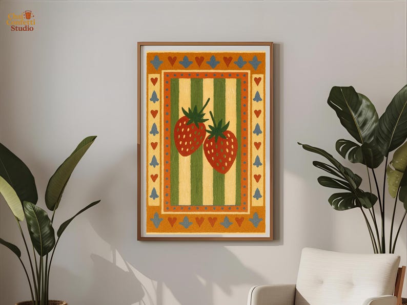 May include: A framed art print featuring two red strawberries with green stems on a striped background of yellow and green. The artwork has a border with hearts and tree-like shapes in orange, blue, and yellow. The print is in a wooden frame.
