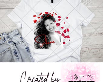 Könnte beinhalten: Weißes T-Shirt mit einem Schwarzweißbild von Selena, um das rote Rosenblätter fallen. Der Text "Selena" ist in Schwarz mit rotem Glitzer-Effekt geschrieben. Das T-Shirt wurde von Gifts by Selena entworfen.
