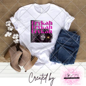 May include: White t-shirt featuring a pink and black graphic design with the name "Erykah" repeated three times. The graphic also includes a photo of a woman with a microphone.