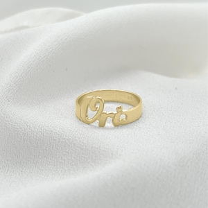 May include: Gold ring with the name "Ora" spelled out in cursive.