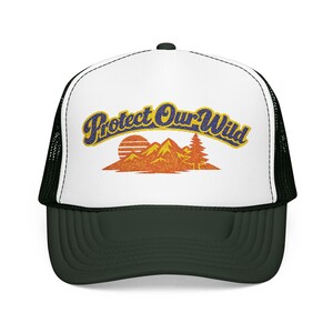 May include: A dark green and white trucker hat. The front panel is white, with the text "Protect Our Wild" in yellow and blue. A graphic of mountains, a setting sun, and a pine tree is below the text. The back and brim are dark green.