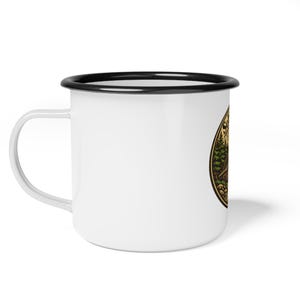 May include: White enamel camping mug with a black rim and handle. The mug features a nature-themed graphic with trees, mountains, and a bear. The design is in shades of green, brown, and yellow, creating a vintage aesthetic.