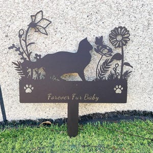 May include: Black metal silhouette of a cat with flowers and the text "Forever Fur Baby" on a brown metal stake.