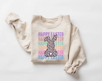 May include: A beige sweatshirt with a graphic of a pink and black leopard print bunny with the text "HAPPY EASTER" repeated in rainbow colors.