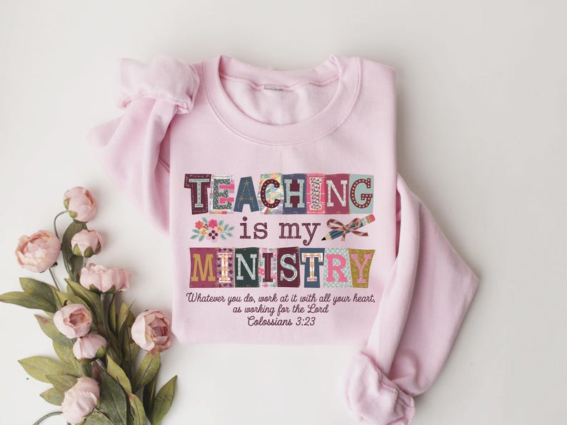 May include: A light pink sweatshirt with the words "TEACHING is my MINISTRY" in colorful block letters. The text "Whatever you do, work at it with all your heart, as working for the Lord Colossians 3:23" is printed below.