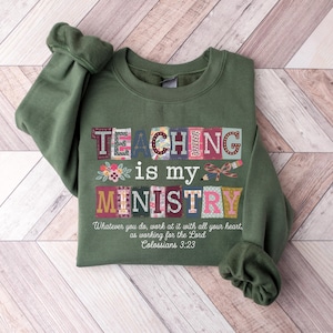 May include: An olive green sweatshirt with the words "TEACHING is my MINISTRY" in colorful block letters. The text "Whatever you do, work at it with all your heart, as working for the Lord, Colossians 3:23" is printed below the main text.