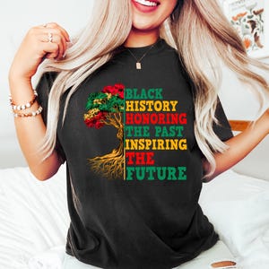 Pu&ograve; includere: T-shirt nera con una grafica ad albero colorata e la scritta "BLACK HISTORY HONORING THE PAST INSPIRING THE FUTURE". L'albero presenta foglie rosse, verdi e gialle.