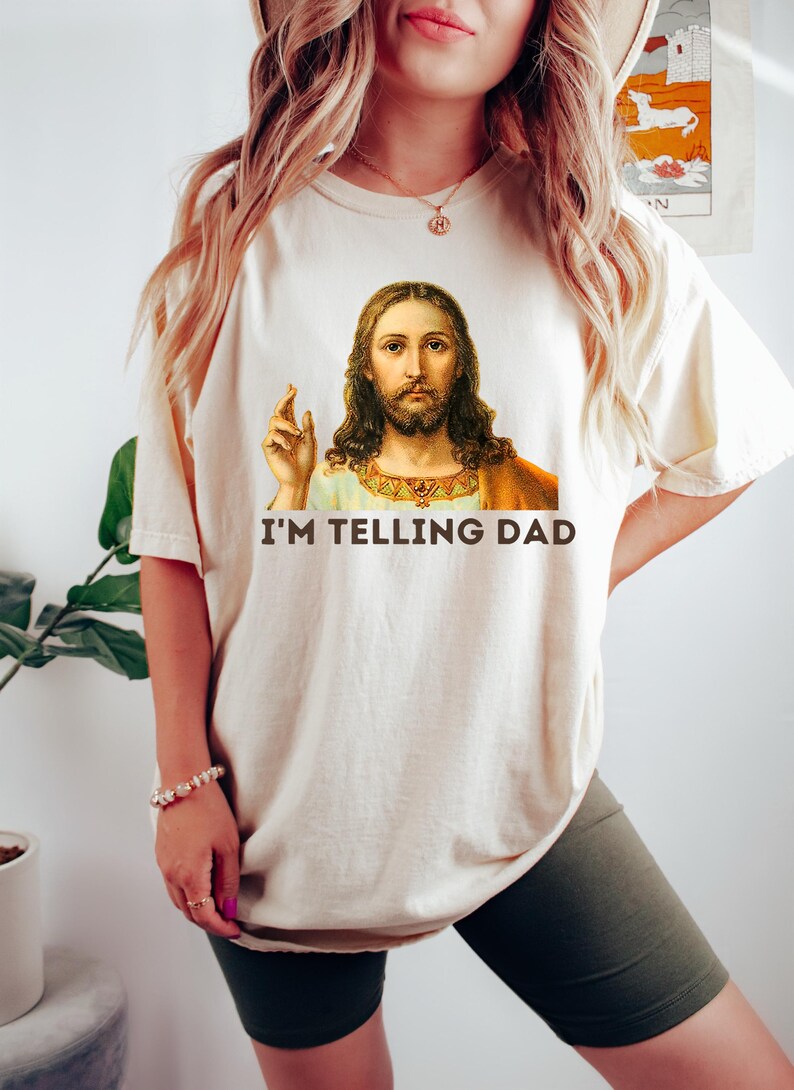 May include: A white t-shirt with a picture of Jesus on it. The text "I'M TELLING DAD" is printed below the image.