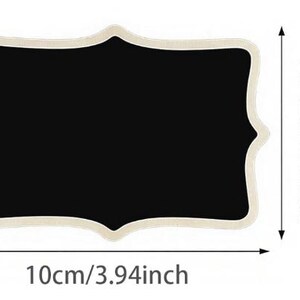 May include: A rectangular chalkboard with a decorative, scalloped edge. The black surface measures 10cm (3.94 inches) wide and 7.5cm (2.95 inches) high. The frame is a light beige color.
