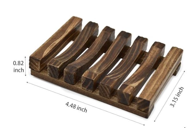 May include: A dark brown wooden soap dish with a slatted design. The dish measures 4.48 inches long, 3.15 inches wide, and 0.82 inches high. The soap dish is made of wood and has a natural finish.