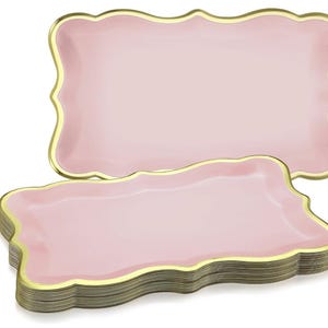May include: Pink rectangular paper plates with a scalloped edge and gold trim. The plates are stacked and arranged to show the design. The plates are a light pink color.