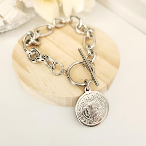 May include: A silver chain bracelet with a toggle clasp and a silver Saint Christopher medal pendant.