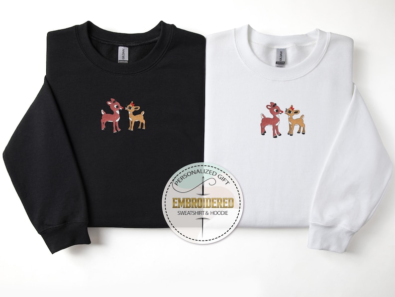 Peut inclure: Deux sweat-shirts noirs et blancs avec des images brod&eacute;es d'un couple de rennes rouge et brun. Le texte "Cadeau personnalis&eacute;" et "Sweat-shirt et sweat &agrave; capuche brod&eacute;" est sur un autocollant rond blanc.