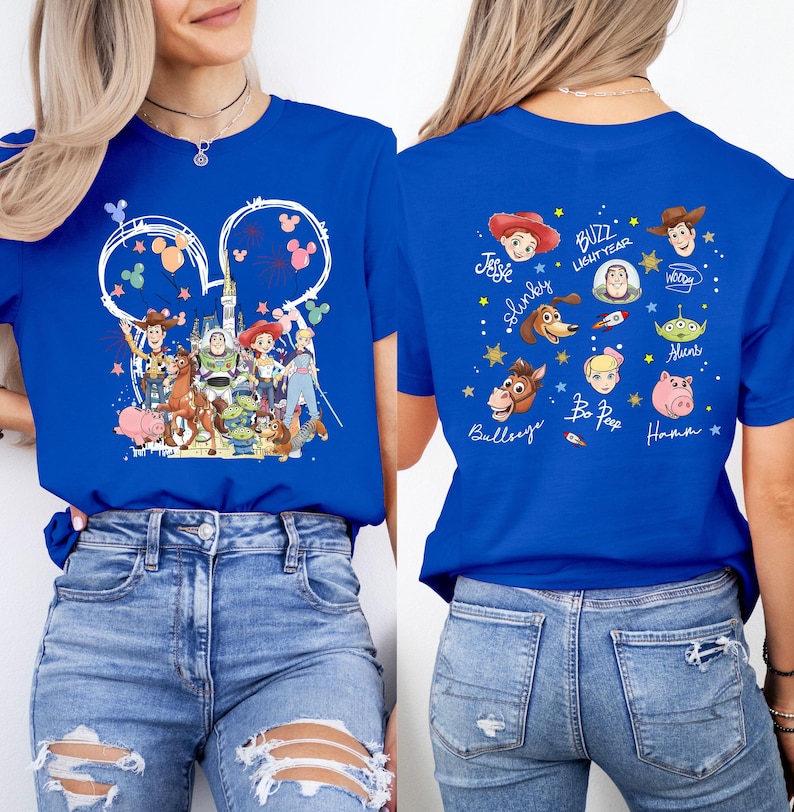 Puede incluir: Camiseta azul real con un dise&ntilde;o tem&aacute;tico de Disney. La parte delantera muestra un collage de personajes de Toy Story dentro de un contorno de oreja de Mickey Mouse. La parte trasera muestra ilustraciones y nombres de personajes individuales.