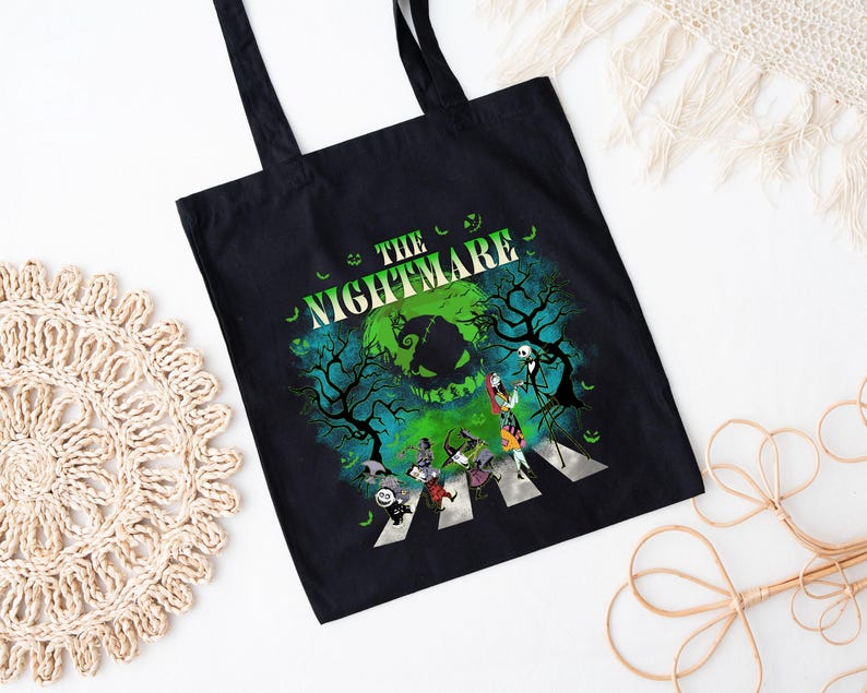 Pode incluir: Sacola preta com um gr&aacute;fico de "O Estranho Mundo de Jack". O design mostra personagens atravessando uma faixa de pedestres com um fundo verde e azul assustador. As palavras "THE NIGHTMARE" s&atilde;o impressas acima da imagem.