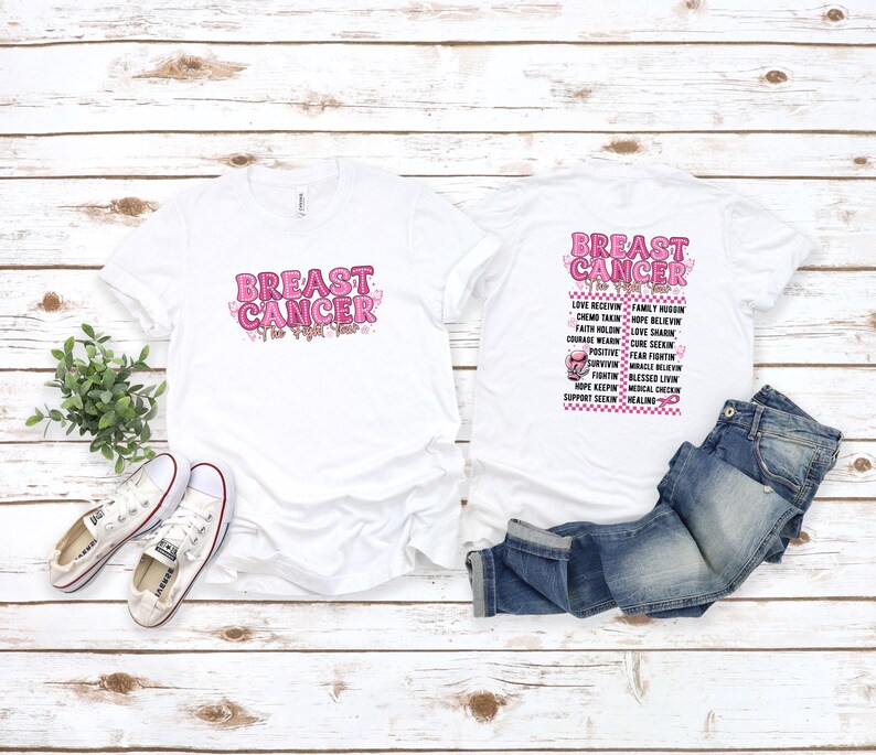 May include: Two white t-shirts with the words "BREAST CANCER" in pink, with a pink ribbon design. One shirt has the text on the front, the other on the back with a list of related words. A pair of white sneakers and blue jeans are also in the image.