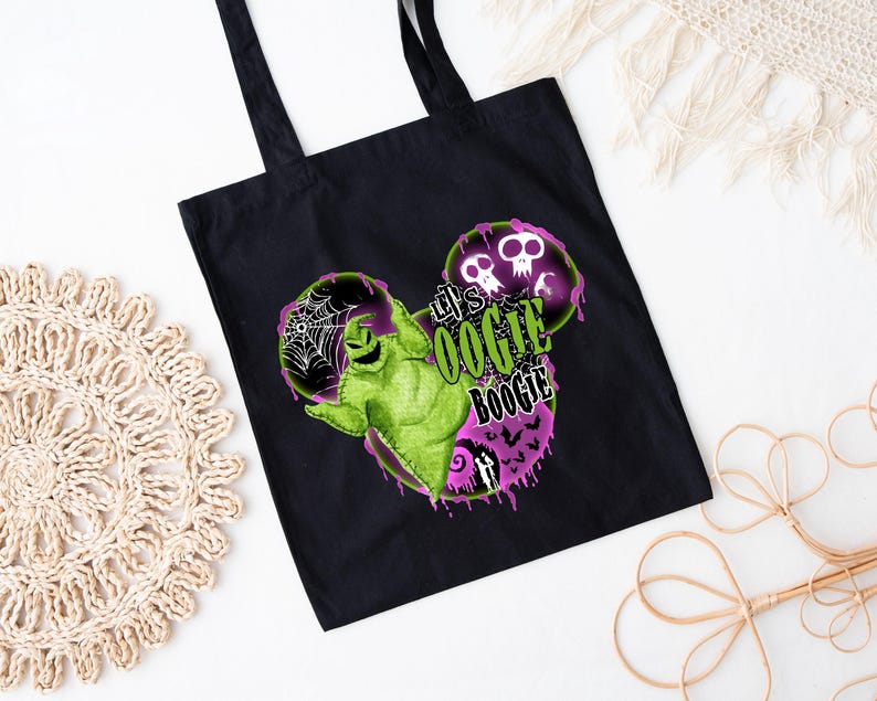 May include: Black tote bag with a green Oogie Boogie character design and the text "Let's Oogie Boogie" in green and white. The design includes purple and pink accents, spiderwebs, and skulls. The bag has black handles.