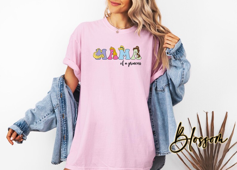 K&ouml;nnte beinhalten: Pinkes T-Shirt mit einem Aufdruck von Disney-Prinzessinnen, die "MAMA of a princess" buchstabieren.