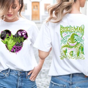 May include: White t-shirts with graphic designs. One shirt features a green and purple Oogie Boogie design in a Mickey Mouse shape with the text "It's Oogie Boogie". The other shirt has a green Oogie Boogie design with the text "Boogie Man".