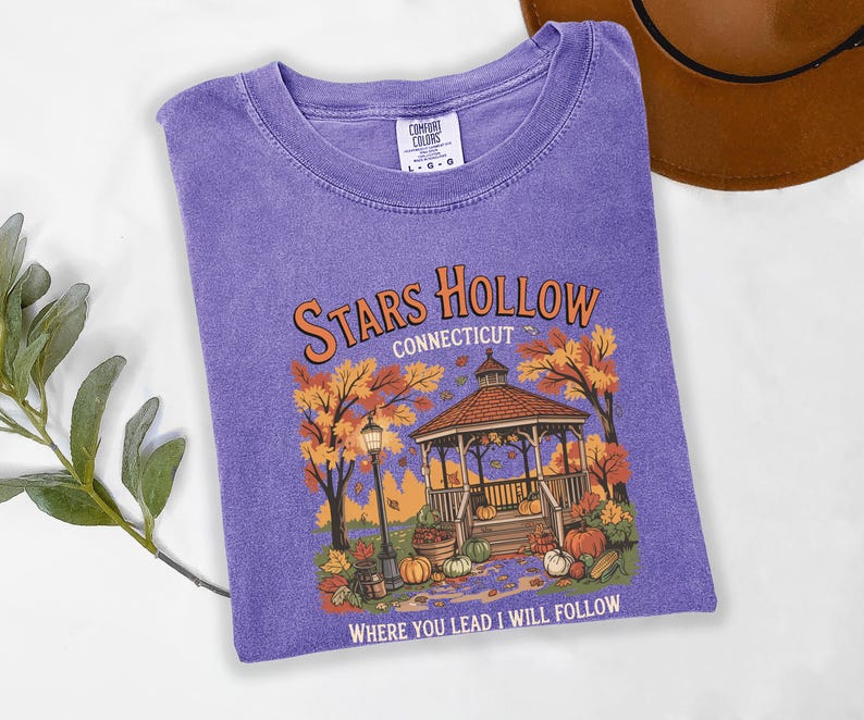May include: A purple Comfort Colors t-shirt featuring a graphic of a gazebo in autumn with the text "Stars Hollow Connecticut" and "Where You Lead I Will Follow". The design includes pumpkins, trees, and a lamppost.