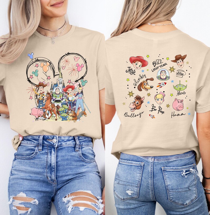 Puede incluir: Camiseta beige con un gr&aacute;fico colorido de los personajes de Toy Story de Disney en la parte delantera y trasera. El dise&ntilde;o frontal incluye orejas de Mickey Mouse con fuegos artificiales e ilustraciones de personajes. La parte posterior muestra nombres e ilustraciones de personajes.